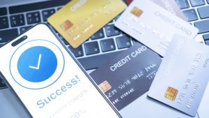 completes online transaction using a smartphone, displaying a Success message. credit cards on a laptop keyboard, symbolizing successful digital payments, online shopping, financial transactions.