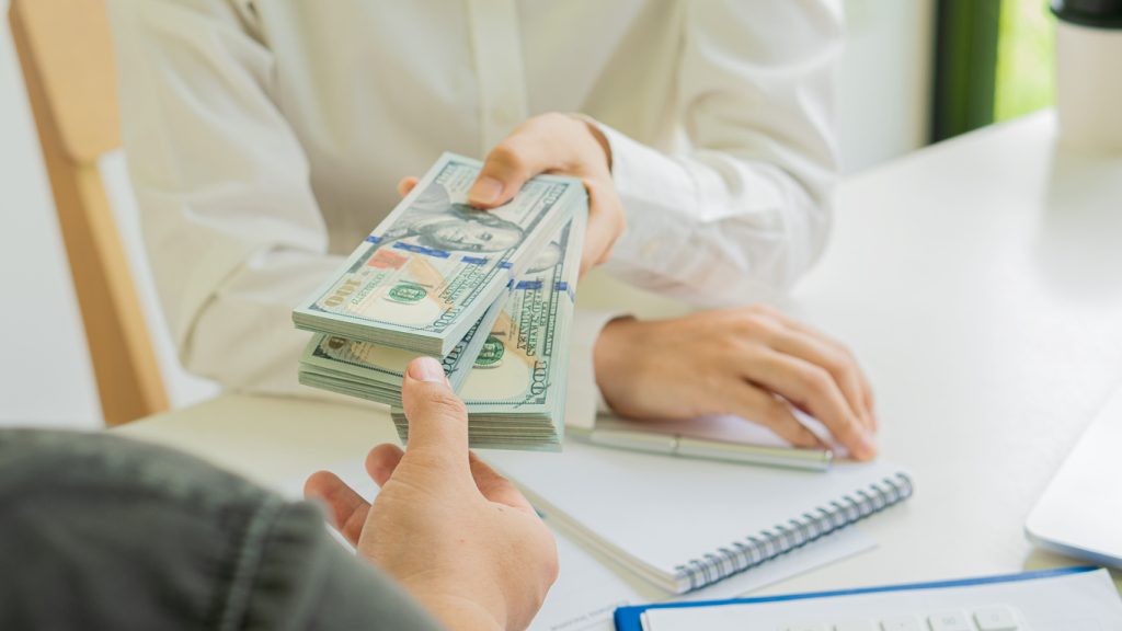 Two businessmen send money to each other to make a deal through cash and investment meetings. With charts and statistics on the tables sat opposite each other. The concept of corruption and bribery